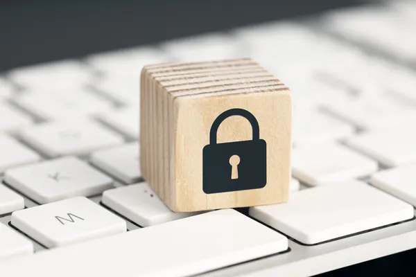 Cubo de madera con un sello de candado colocado sobre el teclado de una computadora, simbolizando las 10 medidas de seguridad en sitios web.
