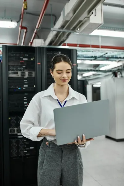 Mujer sosteniendo computadora frente a servidores de alojamiento web, ejemplificando que es webhost