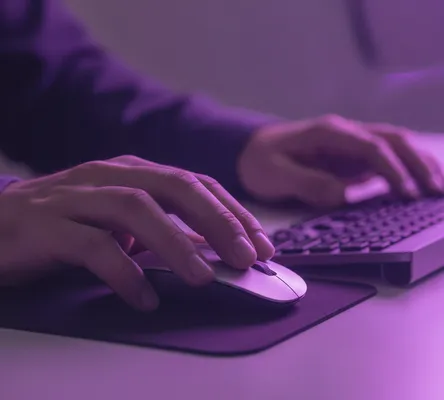 Manos de una persona usando un ratón y teclado, el inicio del proceso de cómo crear una página web desde cero.